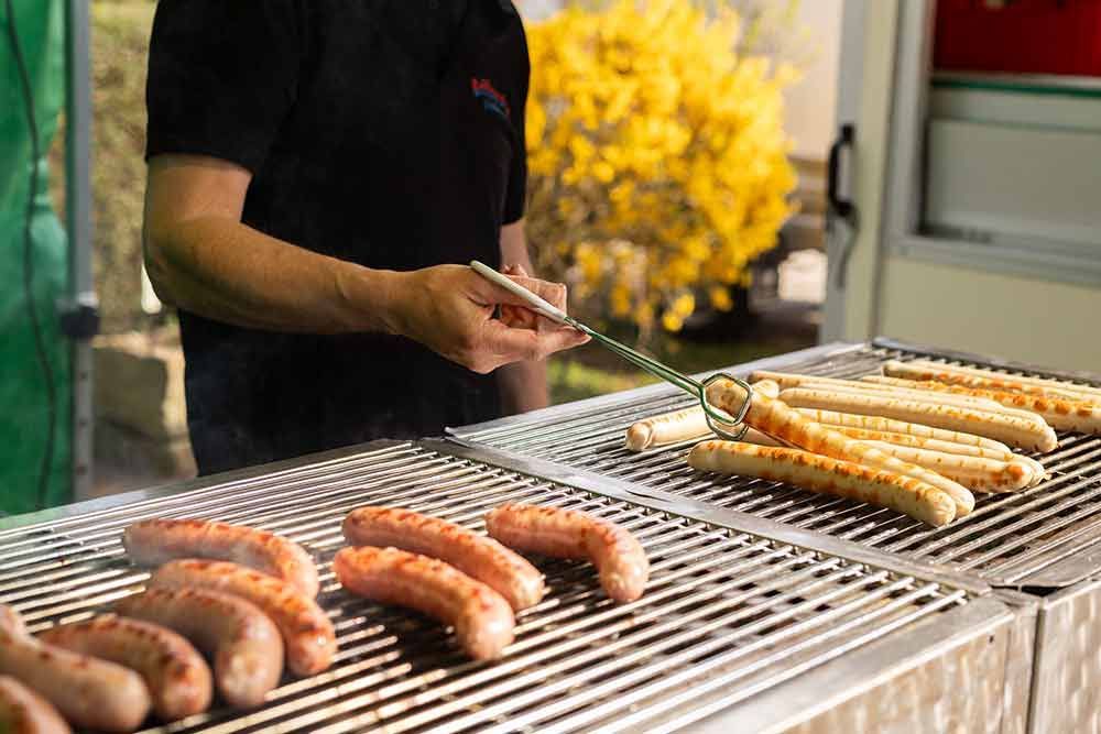 Ein Mann brät Würstchen auf einem Grill.