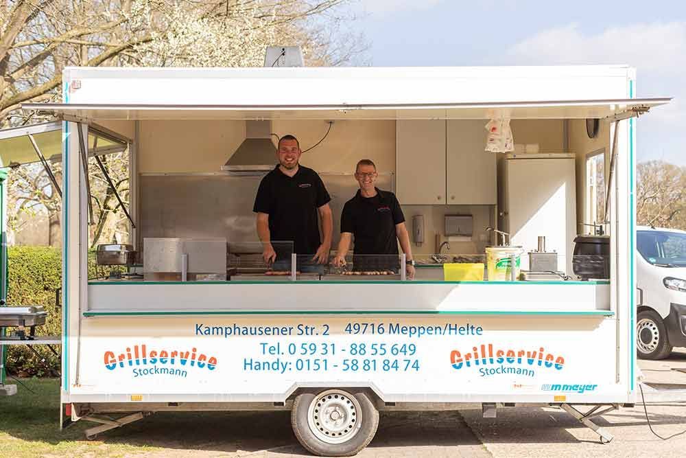 Eine Person brät Würstchen auf einem Grill.