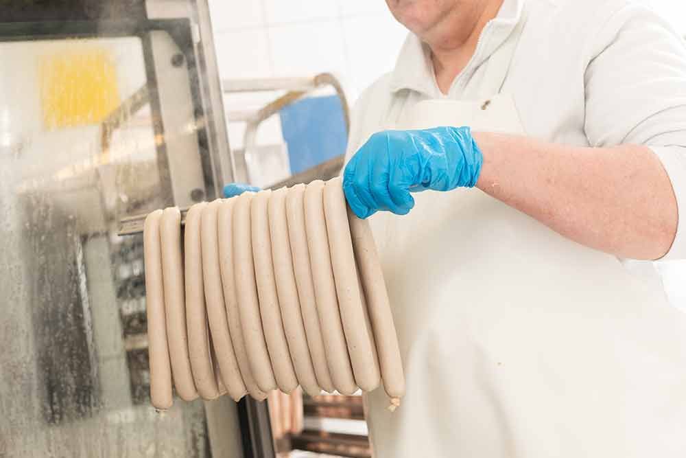 Ein Mann hält einen Haufen Würstchen in seinen Händen.