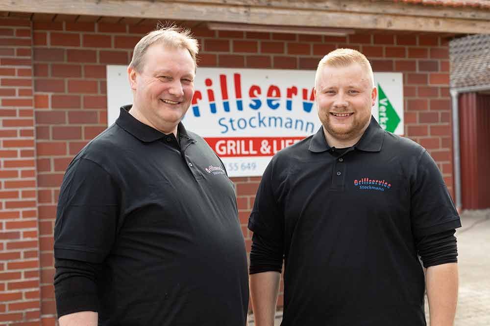 Zwei Männer stehen nebeneinander vor einem Backsteingebäude.
