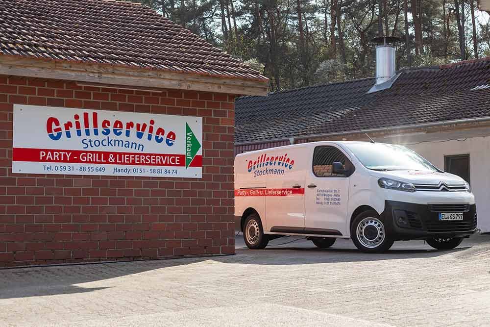 Ein weißer Lieferwagen steht vor einem Gebäude mit der Aufschrift „Grillservice“