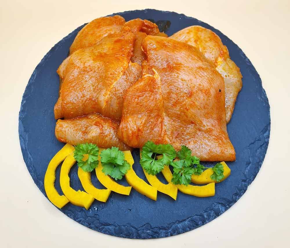 Ein blauer Teller mit Fleisch und Paprika auf einem Tisch.