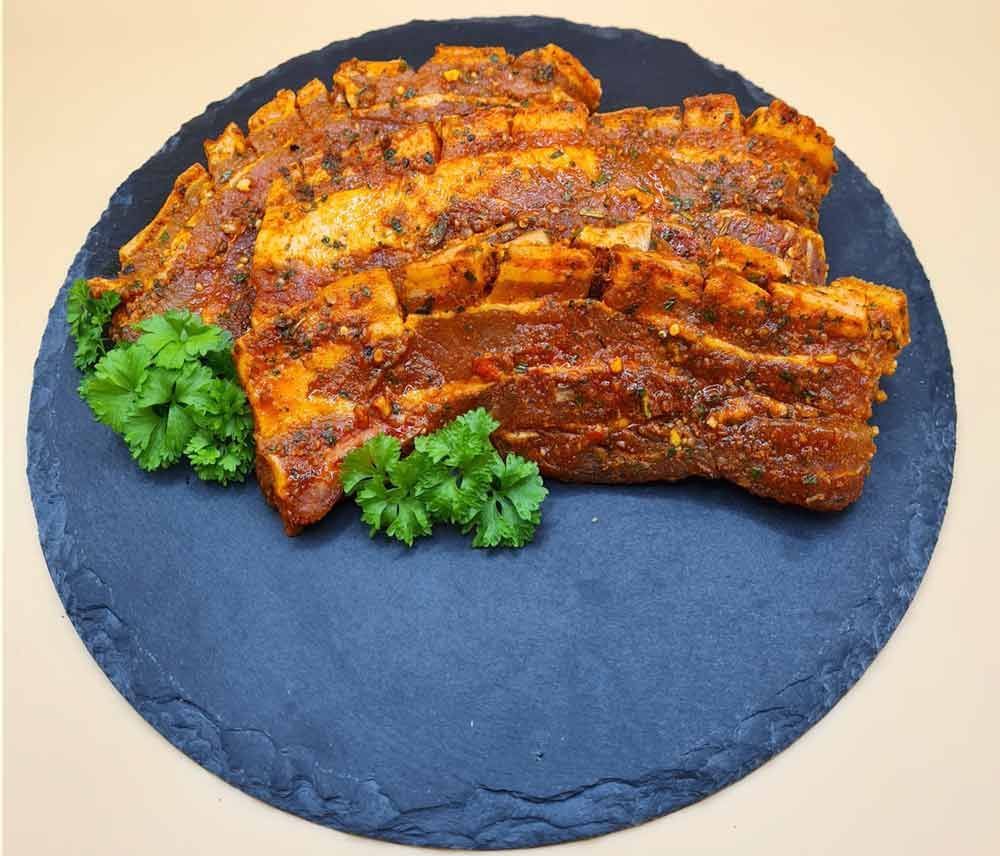 Ein schwarzer Teller mit Fleisch und Petersilie auf einem Tisch.