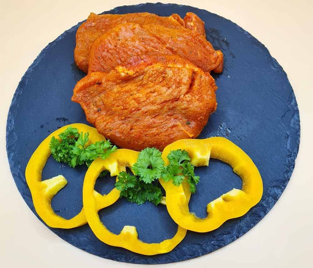 Ein Teller mit Fleisch, Paprika und Petersilie auf einem Tisch.