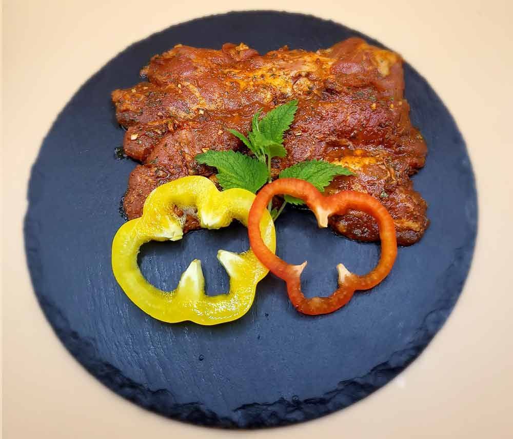 Ein schwarzer Teller mit Fleisch und Paprika auf einem Tisch