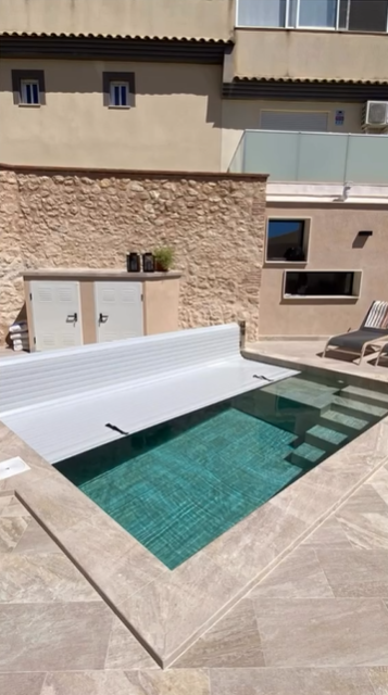 Una mano sostiene un dispensador de productos químicos para piscinas de color azul