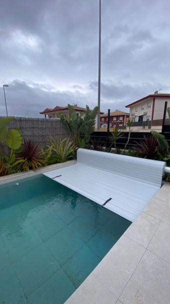 Una piscina rectangular con cubierta de seguridad automática de color gris claro