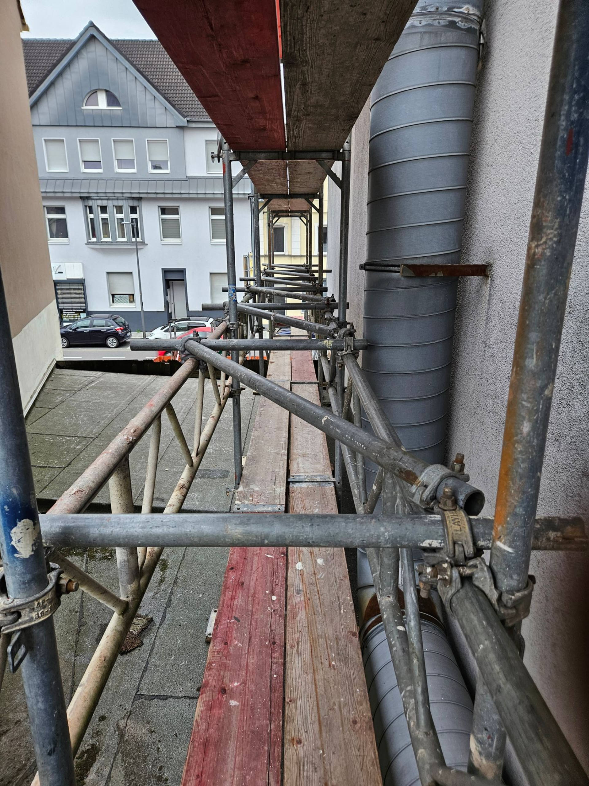 Schmaler Gerüstgang entlang einer Hausfassade.