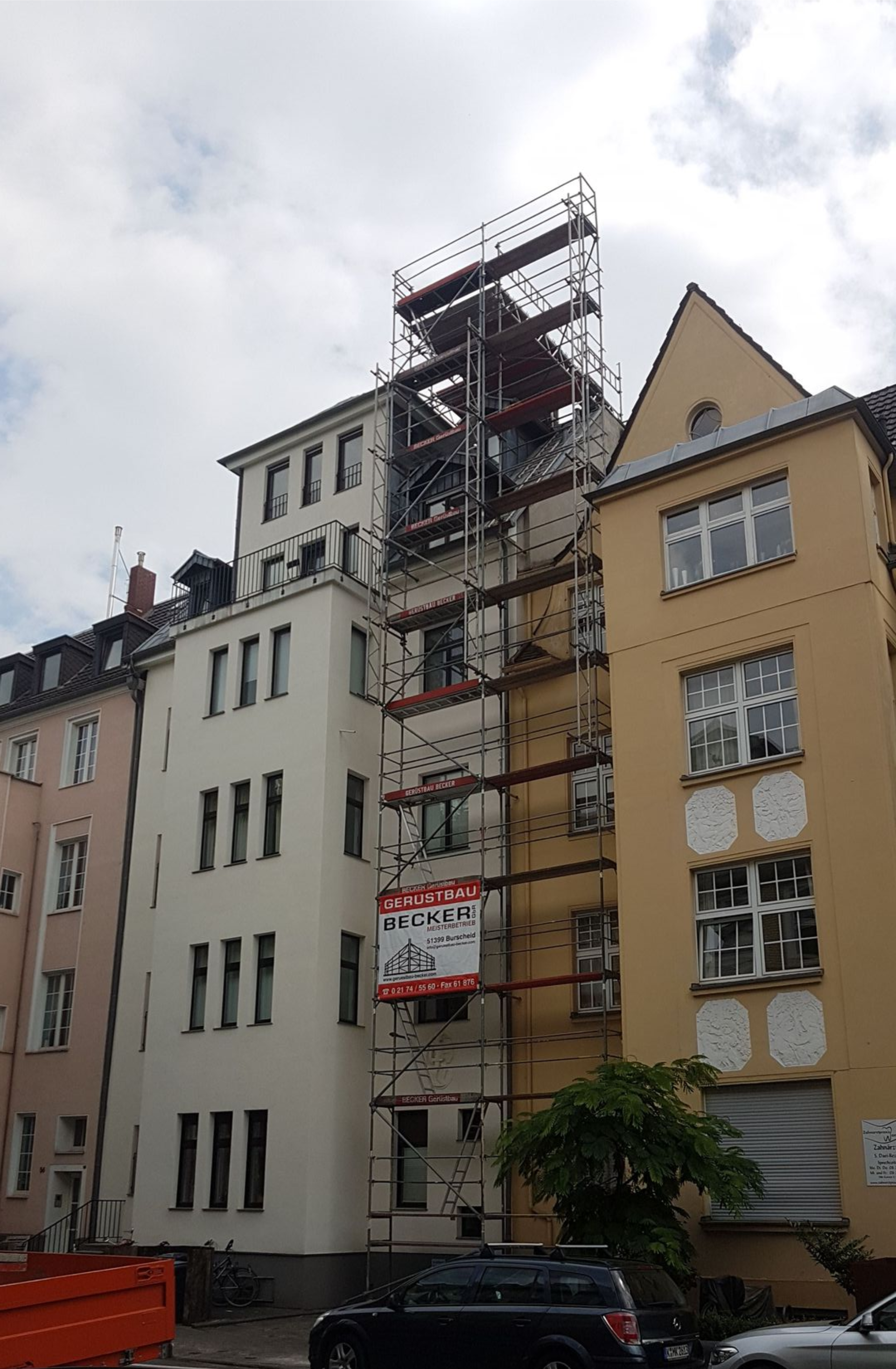 Altbauten in einer Stadtstraße mit eingerüsteten Fassaden.