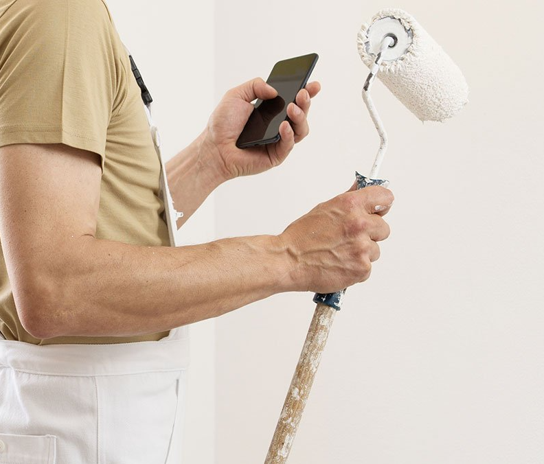 Peintre au téléphone tenant son rouleau