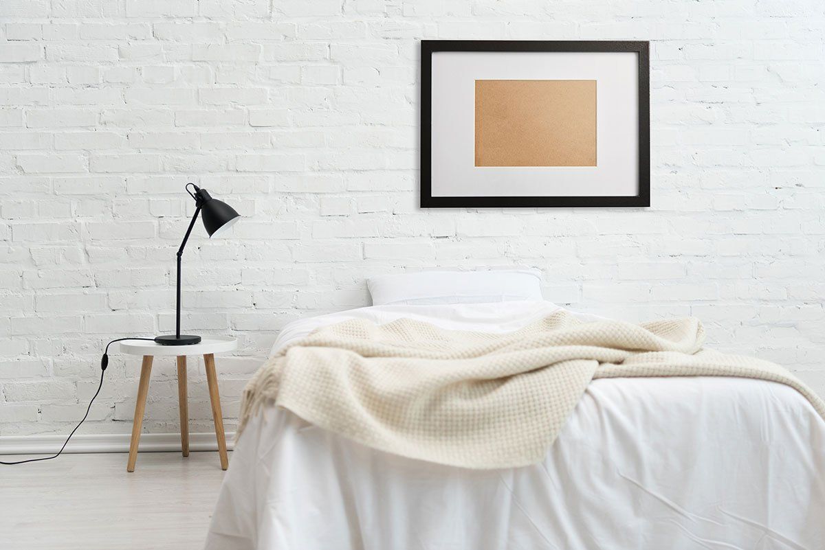 Chambre à coucher moderne avec lit et cadre noir sur mur de briques blanches