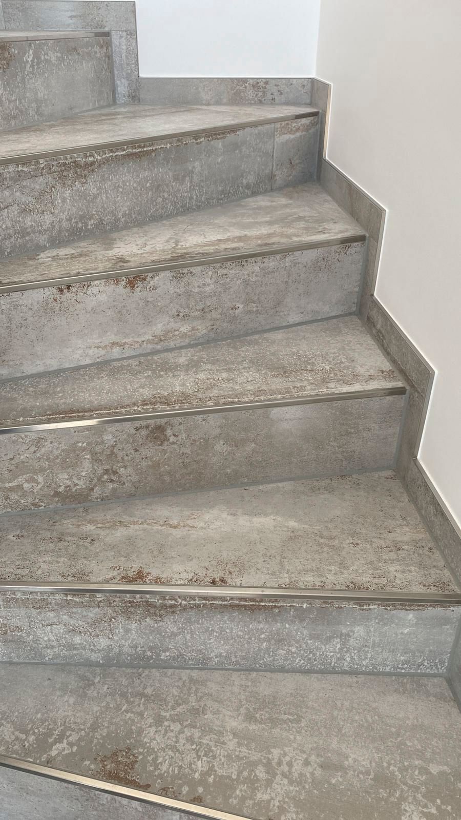 Graue Steintreppe, die sich geschwungen nach oben windet und Gebrauchsspuren aufweist.