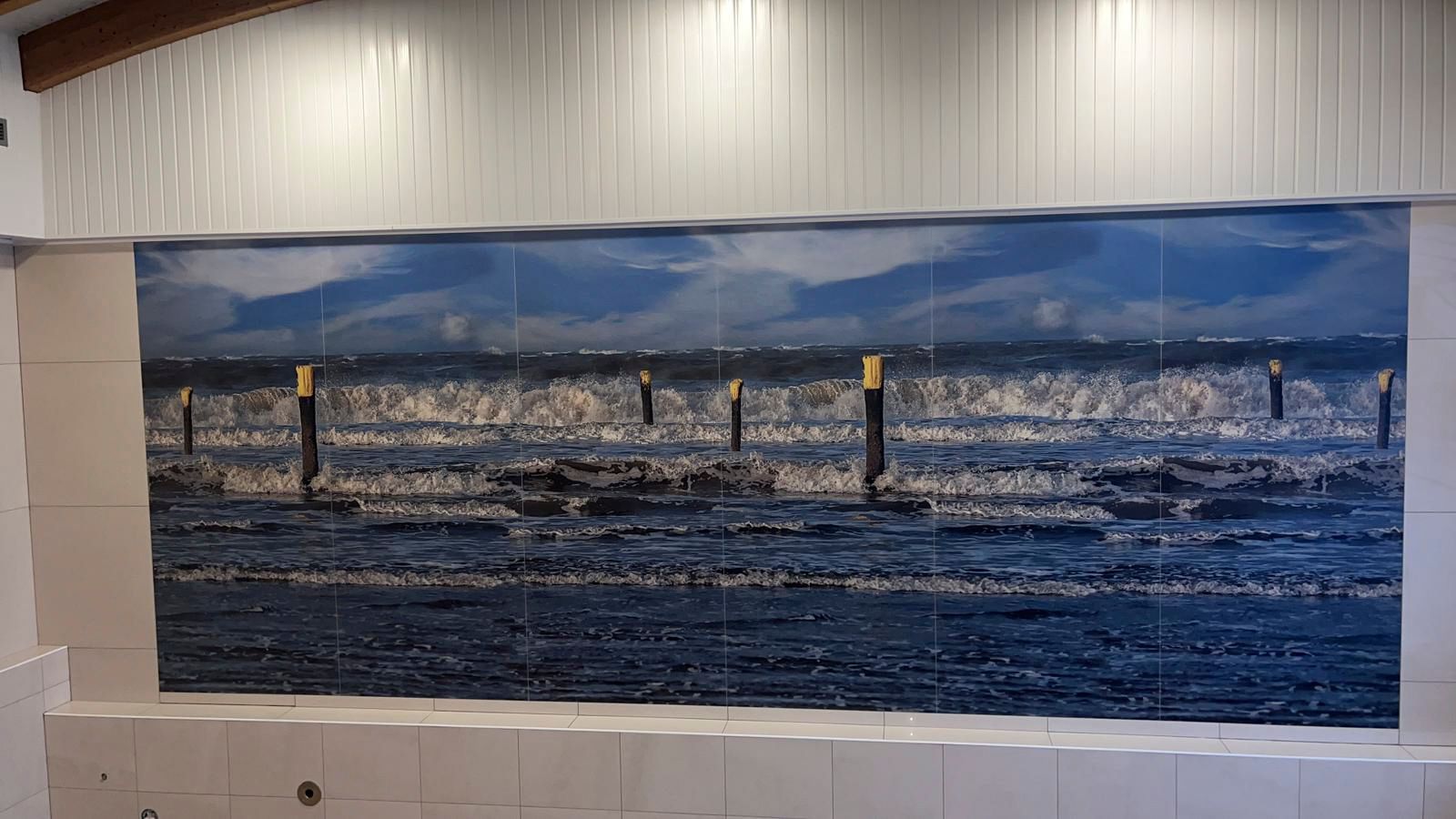 Meereslandschaft als Wandgemälde auf einer gefliesten Wand, mit dunkelblauem Wasser und hellblauem Himmel.