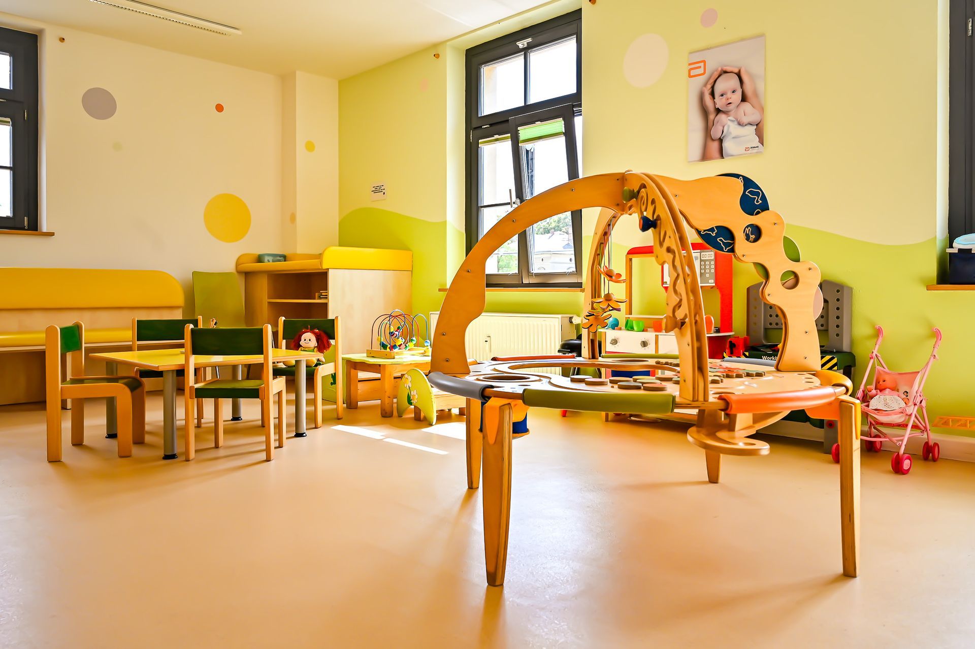 Hell erleuchteter Vorschulraum mit Spielbereich und kleinen Tischen.