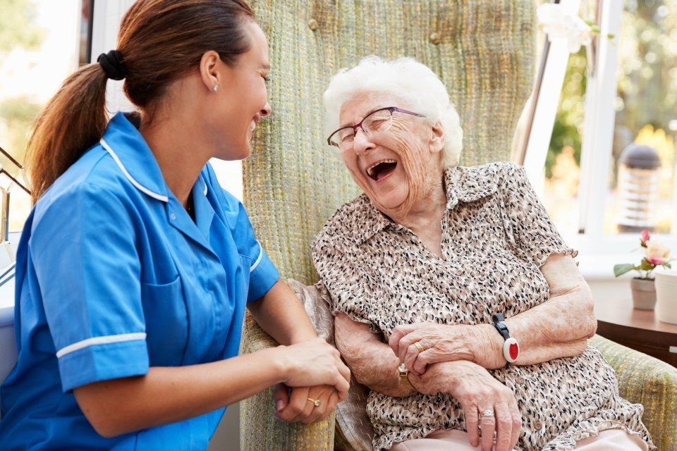 Seniorin lacht mit Altenpflegerin