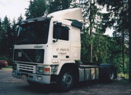 Valkoinen Volvo-puoliperävaunu pysäköitynä ulos ohjaamo katsojaa kohti puiden taustalla.