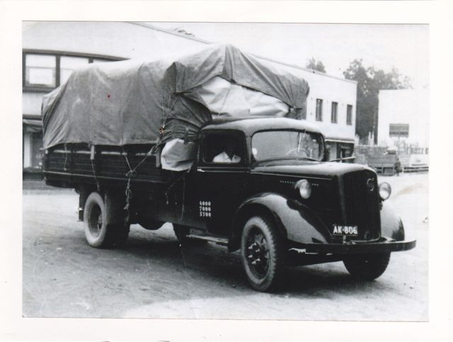 Musta vintage-kuorma-auto, katettu kuorma, pysäköitynä ulkona.