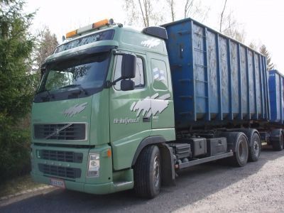 Vihreä Volvo-kuorma-auto, jossa on sinisiä rahtikontteja, pysäköitynä ulkona.