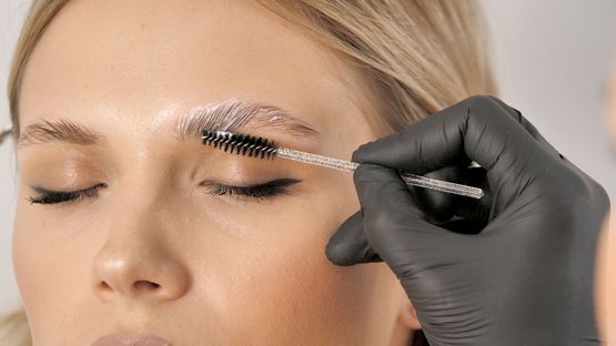 Mitarbeiterin von NAIL & FOOT und E STYLING PRODUCTION behandelt Augenbrauen von Kundin