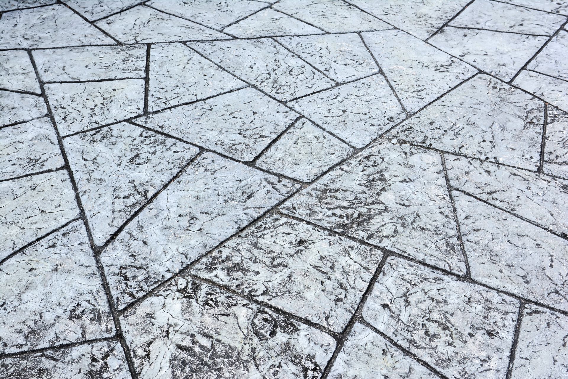 Un primer plano de un piso de concreto con un patrón geométrico.