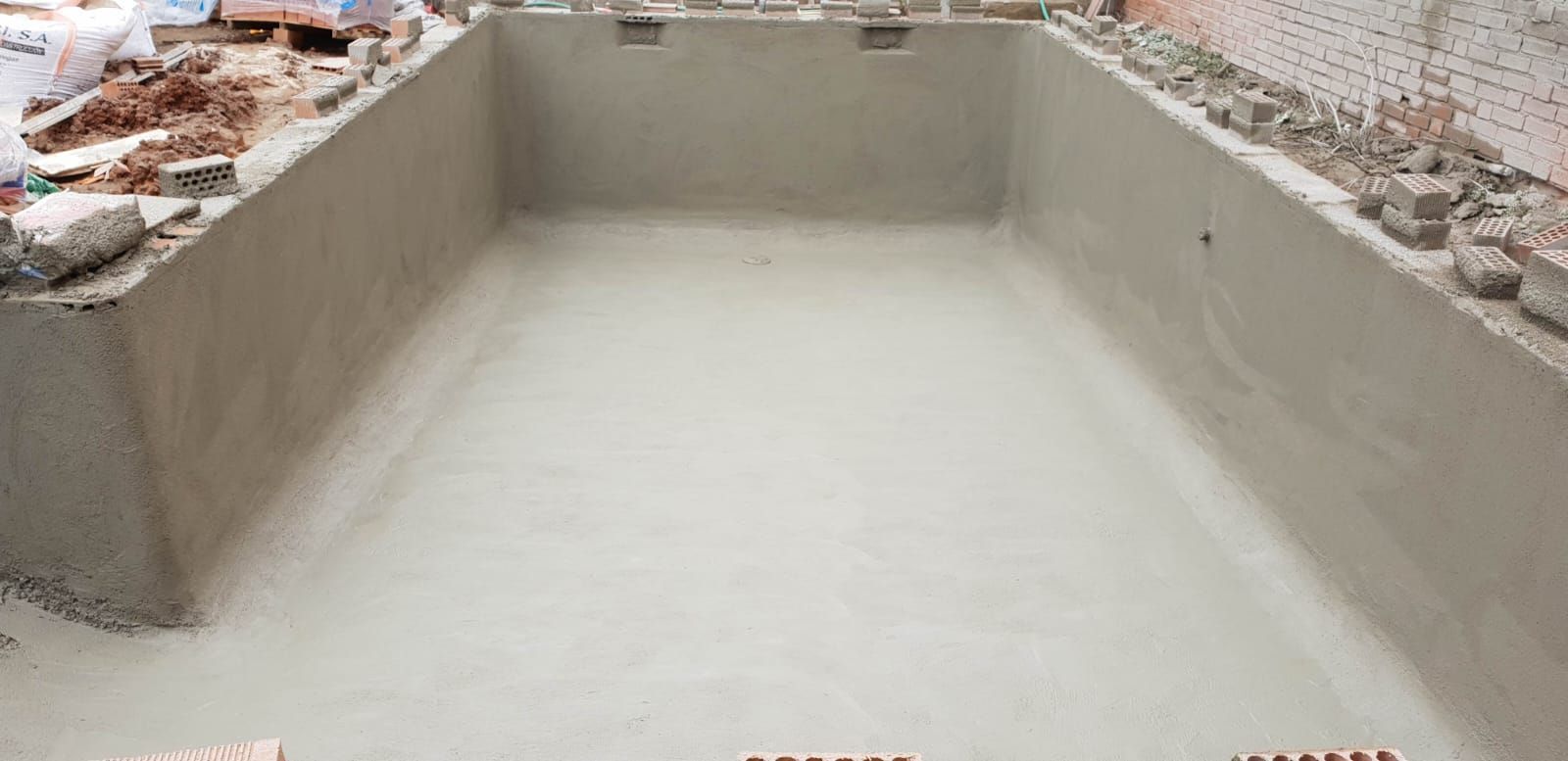 Una gran piscina está rodeada de árboles y una terraza de madera.