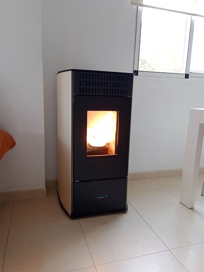 Una estufa de pellets está situada en una sala de estar al lado de una ventana.