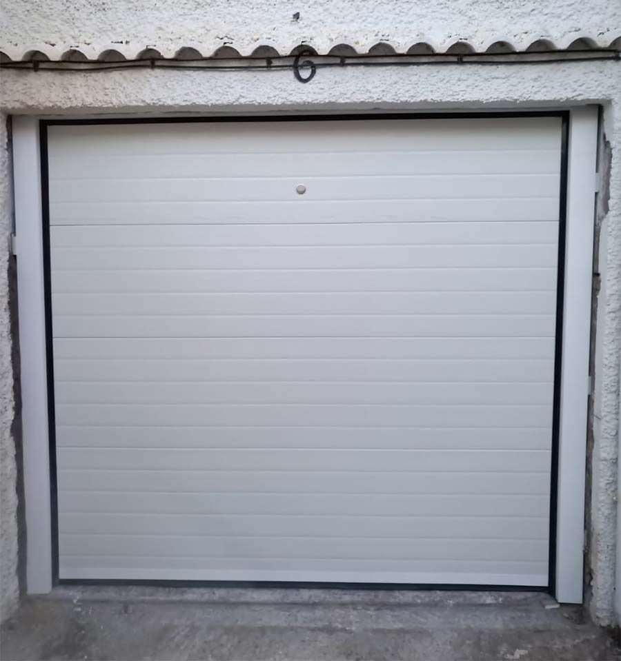 Una puerta de garaje blanca está abierta en un garaje.