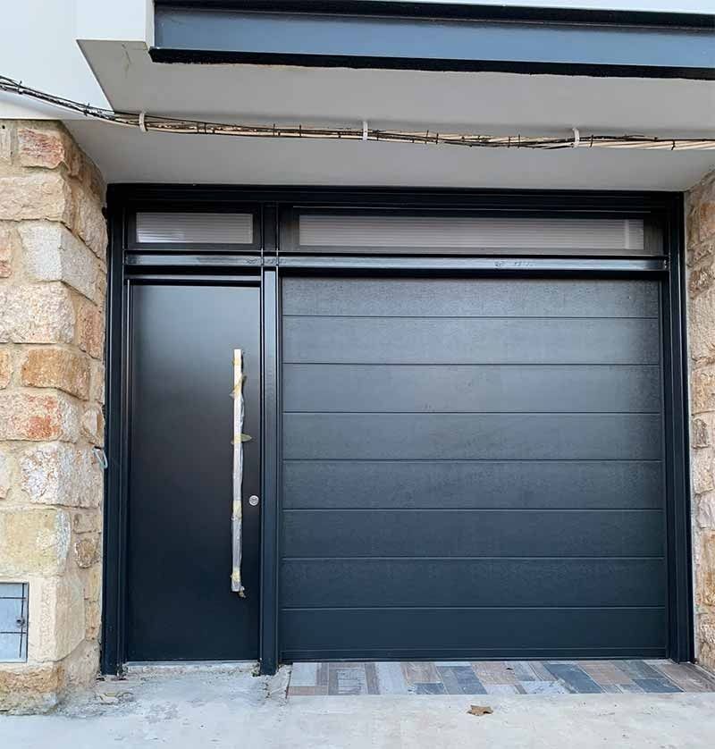 Una puerta de garaje negra con una puerta al fondo.