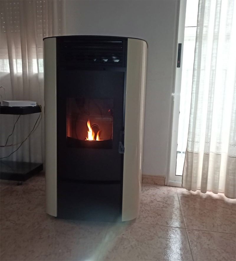 Una chimenea está en una sala de estar junto a una ventana.
