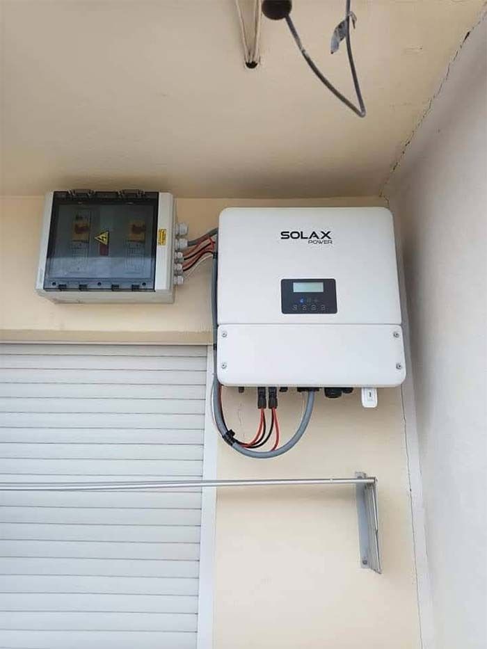 Un inversor de panel solar está montado en una pared al lado de una puerta de garaje.