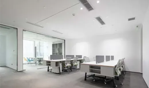 Oficina moderna con escritorios y sillas blancos y paredes de cristal. Espacios de trabajo vacíos.