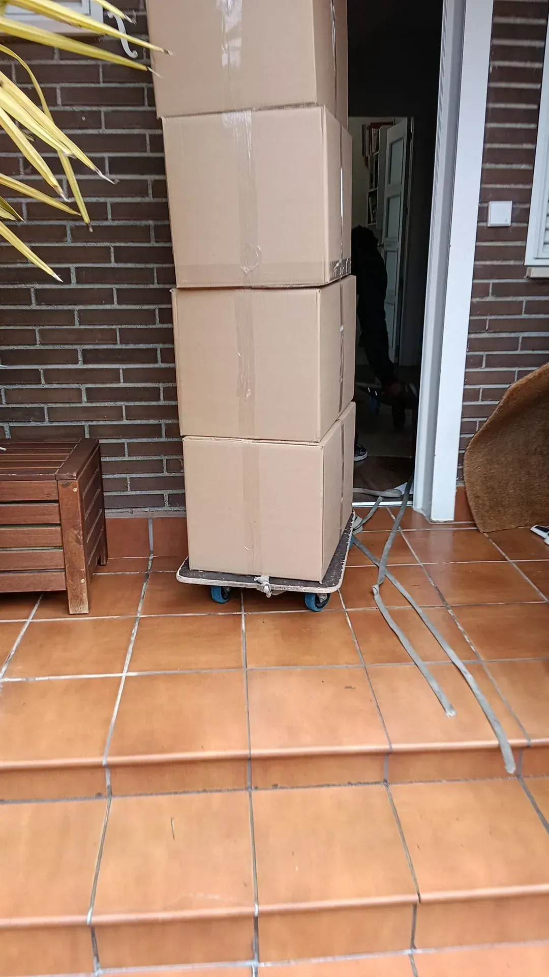 Tres cajas de cartón apiladas en una plataforma rodante, cerca de una puerta.