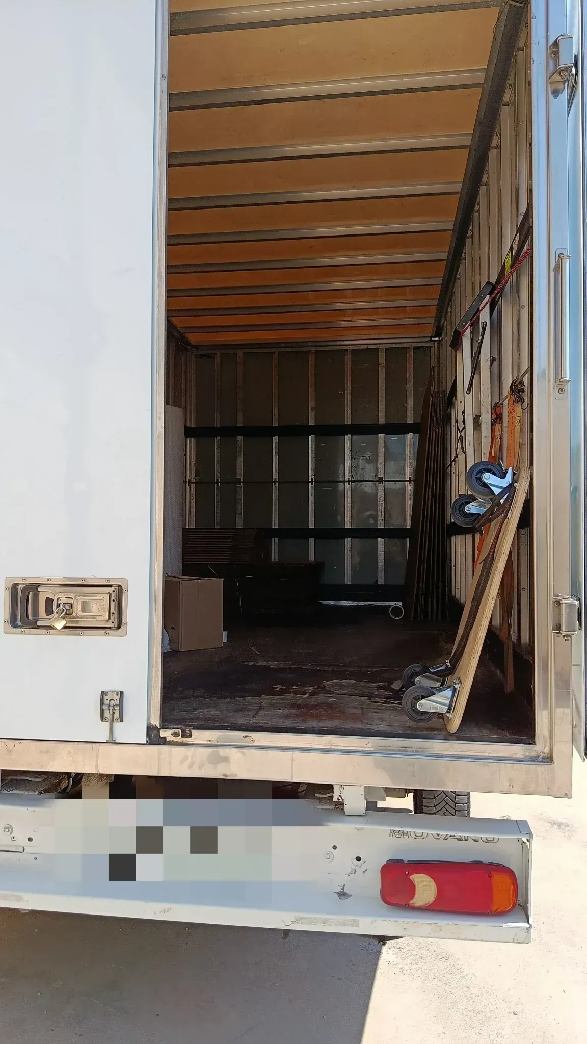 Compartimento de carga abierto de una camioneta blanca. El interior presenta suelo y paneles laterales de madera.