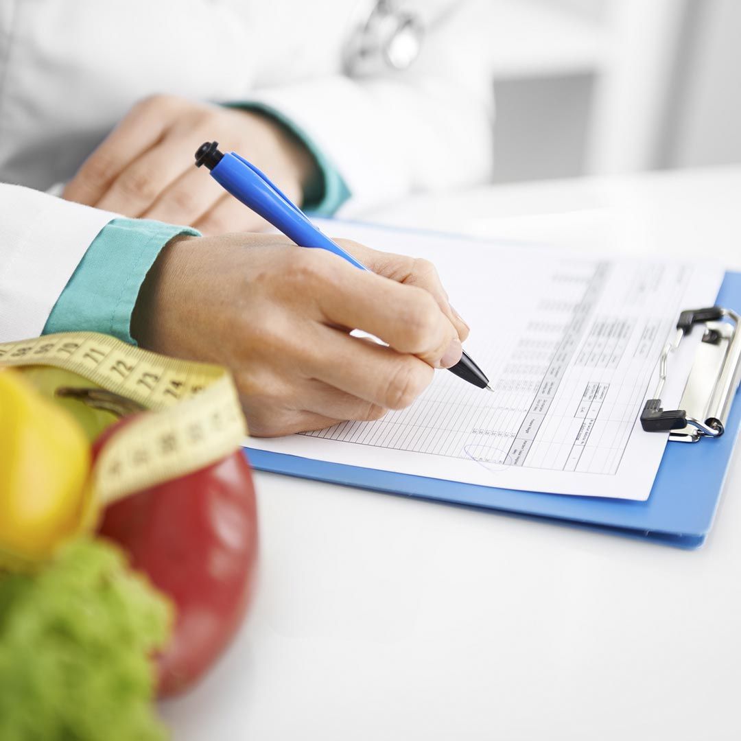 Una persona está escribiendo en un portapapeles junto a frutas y verduras.