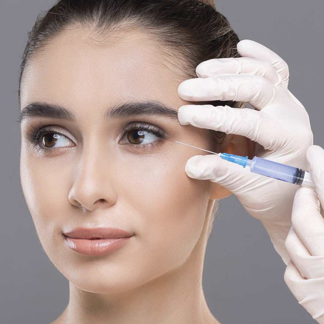 Una mujer recibe una inyección de botox en el ojo.