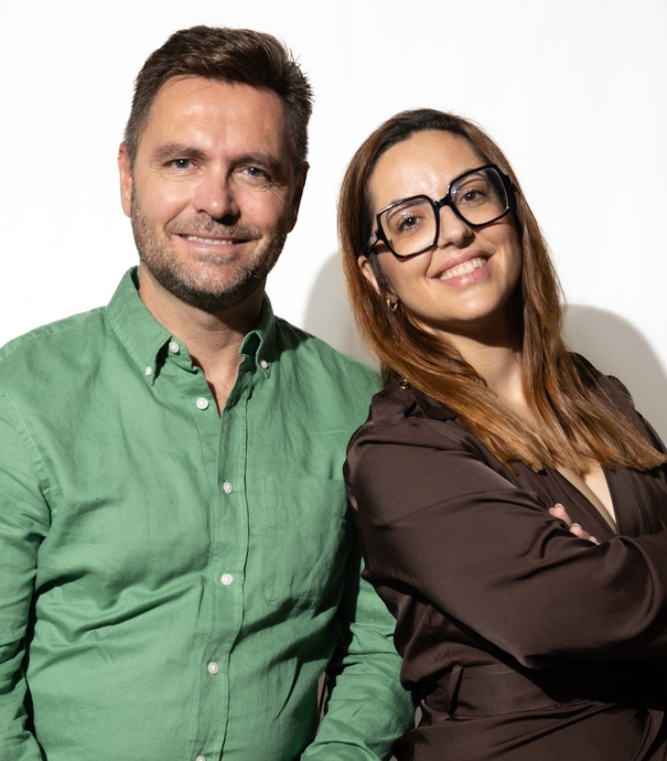 Un hombre y una mujer están sentados en una mesa mirando una tableta.