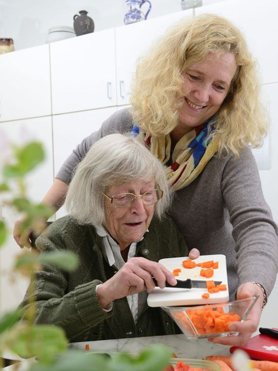 Die Hände einer Person halten sanft die Hand einer anderen Person und tragen Creme darauf auf.