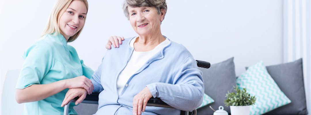 Eine Person legt sanft ihre Hand auf die Hand einer anderen Person, die den Griff eines Gehstocks hält.