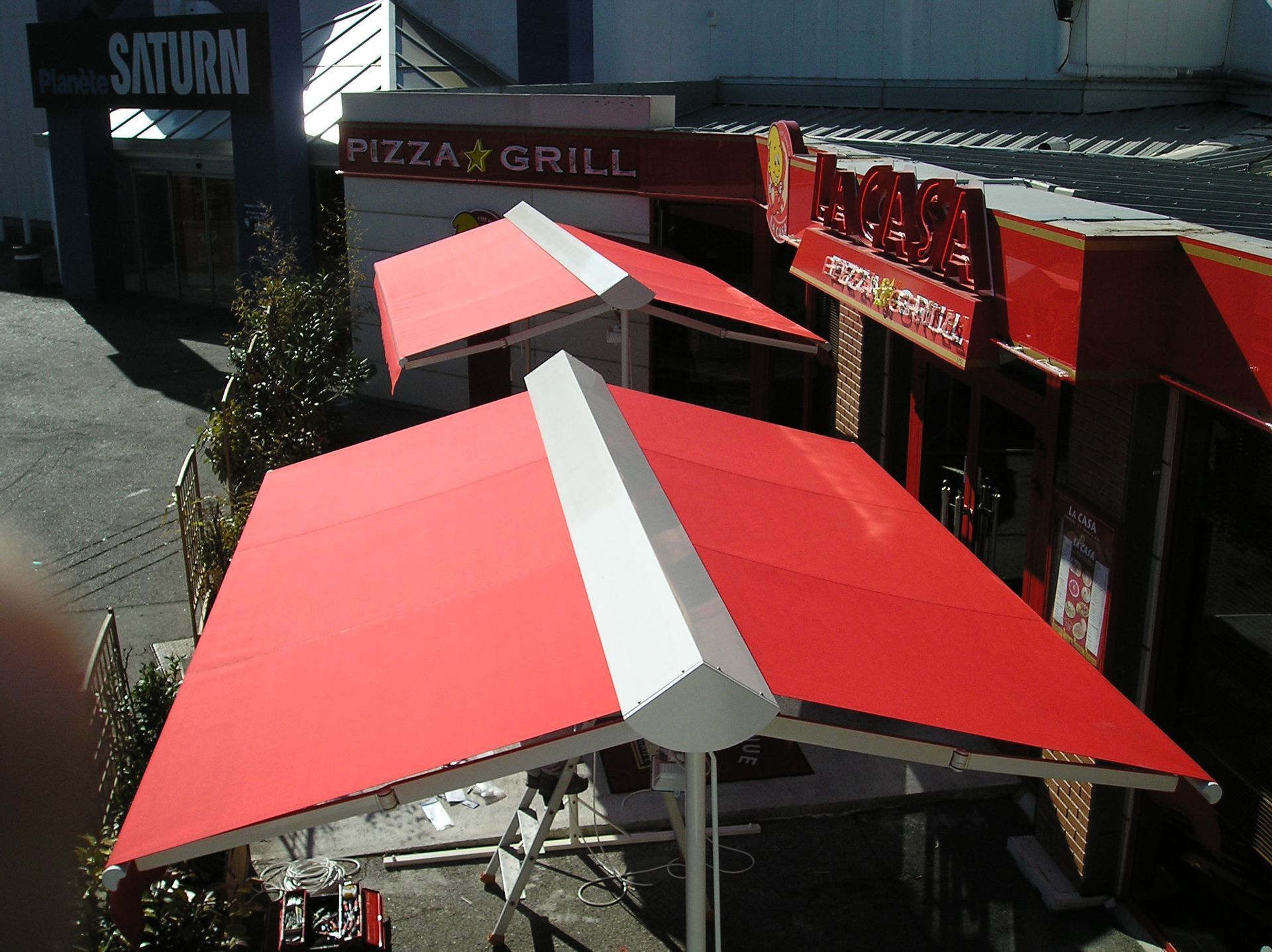 Stores à double pente rouges installés pour une terrasse.
