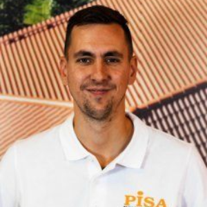 Hymyilevä mies valkoisessa Pisa-poolopaidassa kuviollista taustaa vasten
