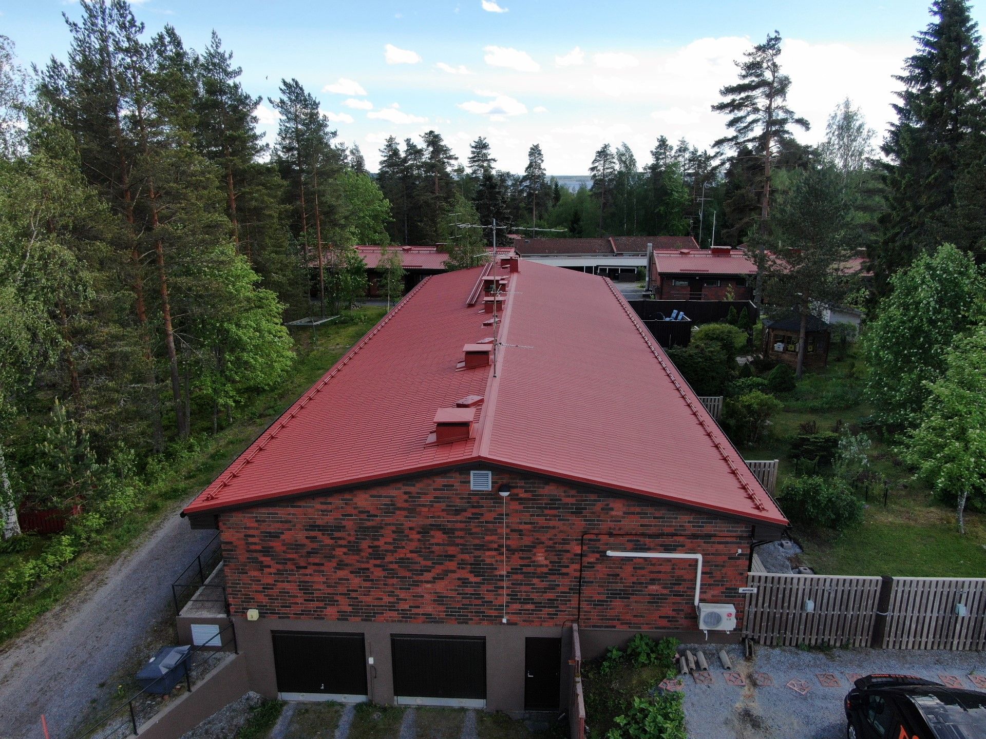 Punakattoinen tiilirakennus tiheiden vihreiden puiden ympäröimänä ylhäältä katsottuna.
