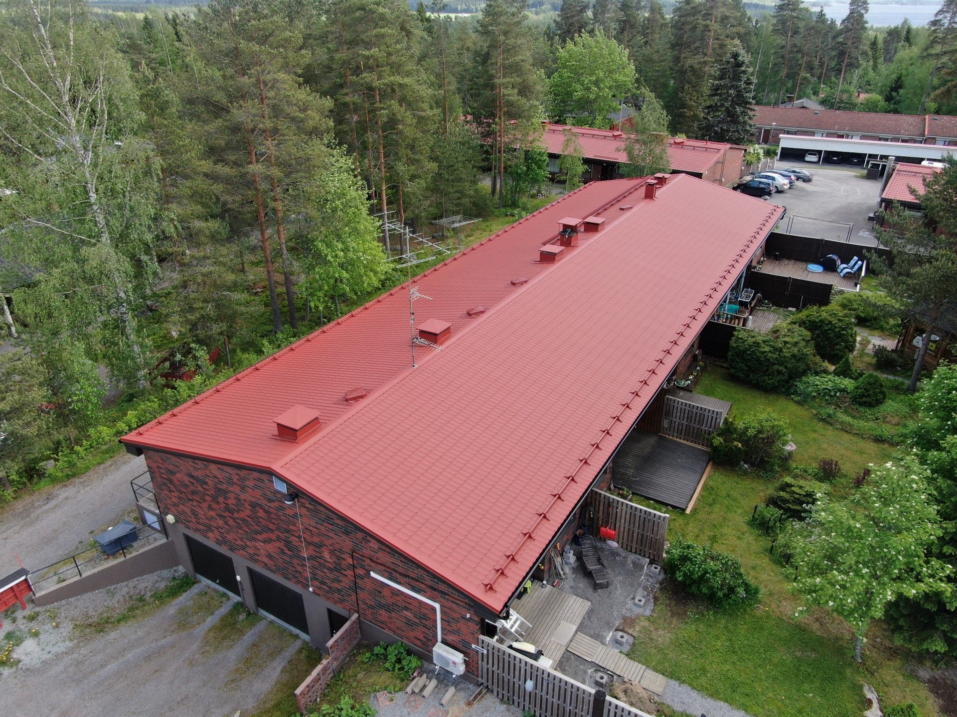 Ilmakuva pitkästä punakattoisesta tiilirakennuksesta, jota ympäröivät puut ja vehreys