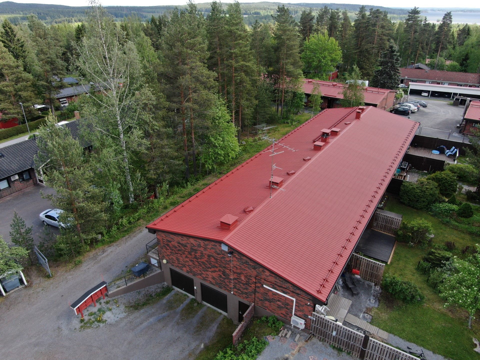 Ilmakuva punakattoisesta tiilirakennuksesta, jota ympäröivät puut ja naapurirakennukset maaseudulla