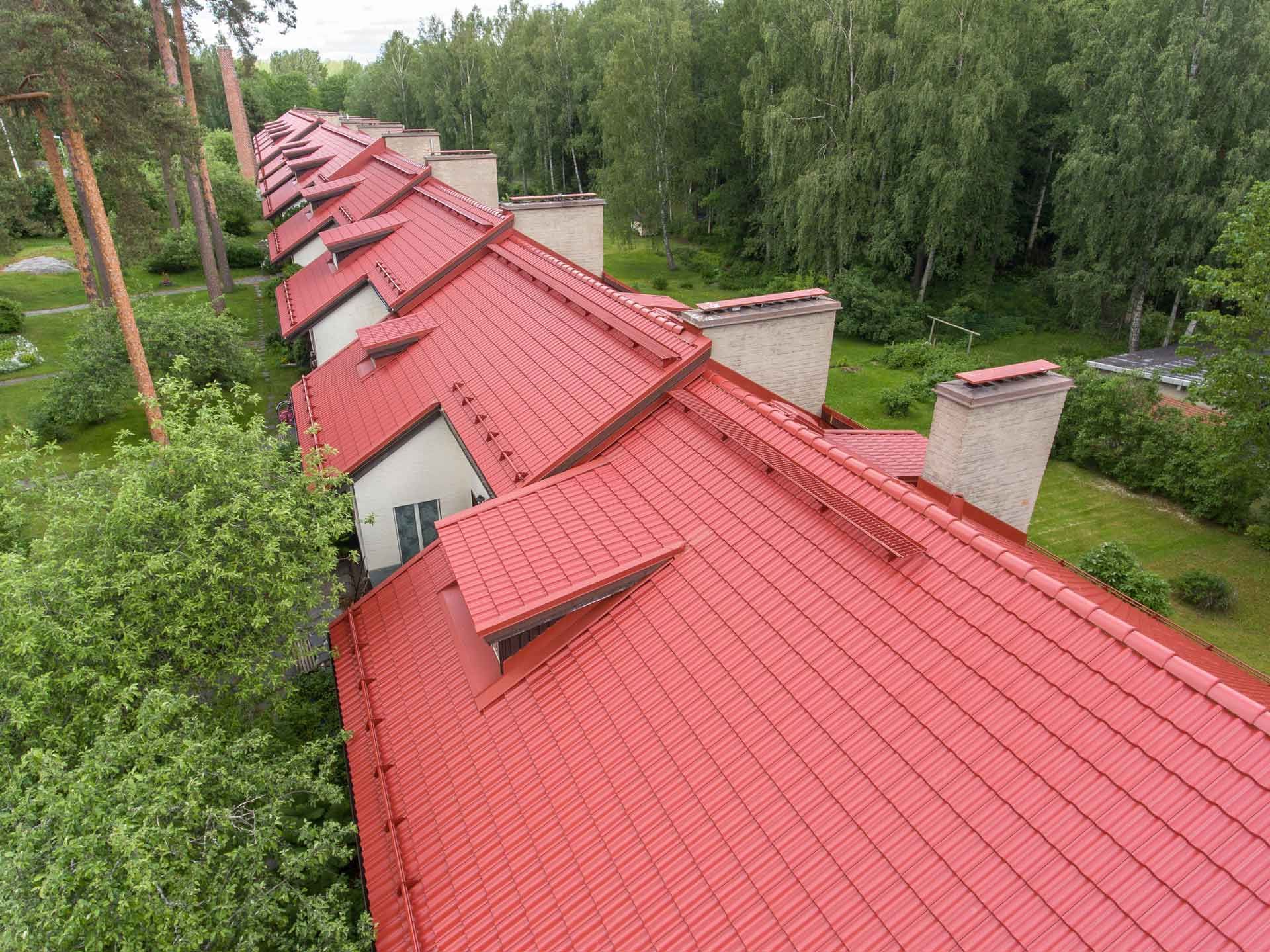Pitkä rivi punakattoisia taloja vihreiden puiden ja nurmikon vieressä