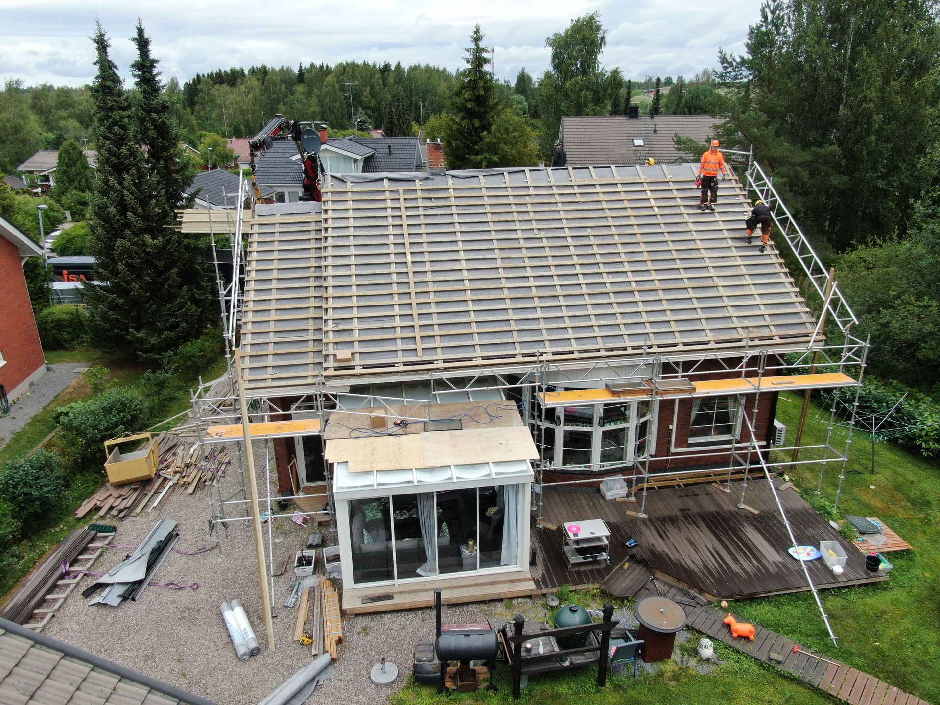Talon katto rakenteilla, työntekijät telineillä ja näkyvillä puurunko