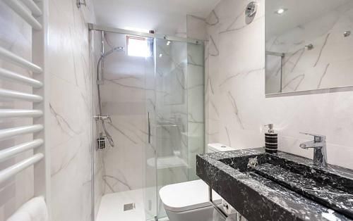 Baño pequeño y moderno con paredes con aspecto de mármol, ducha de cristal y lavabo de piedra oscura.