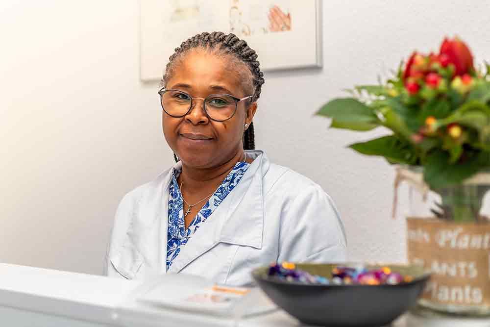 Eine Frau sitzt an einer Rezeption mit einer Blume im Hintergrund .