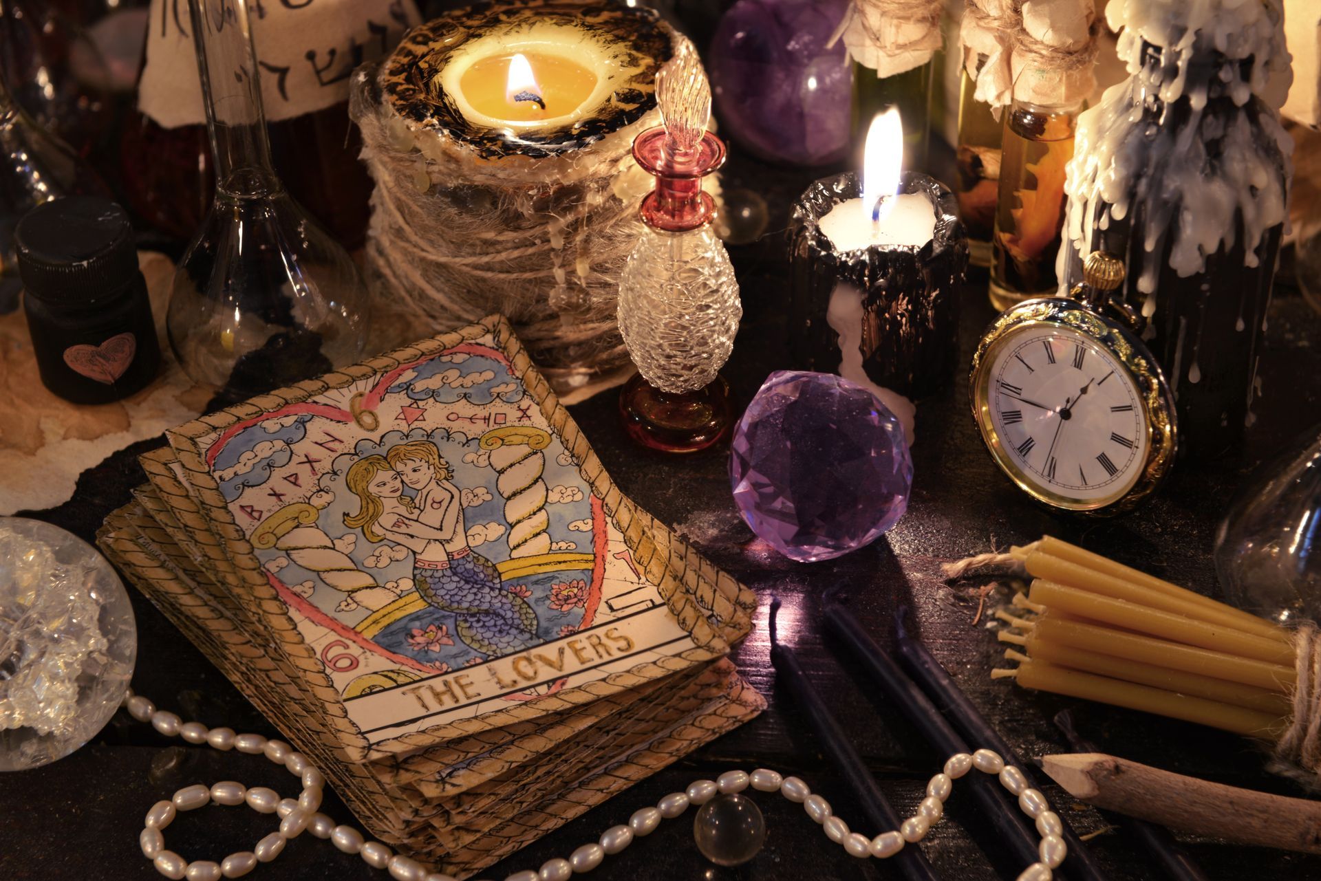 Cartes de tarot où apparaît la carte du Valet, entouré de bougies, de cristaux et de potions.