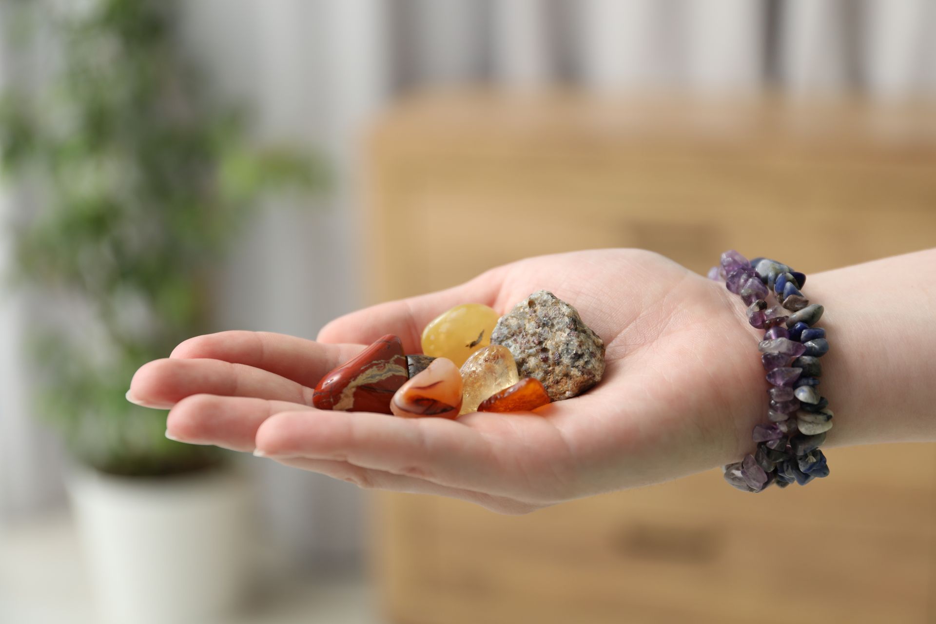 Main tenant plusieurs cristaux colorés, bracelet d'améthyste au poignet.