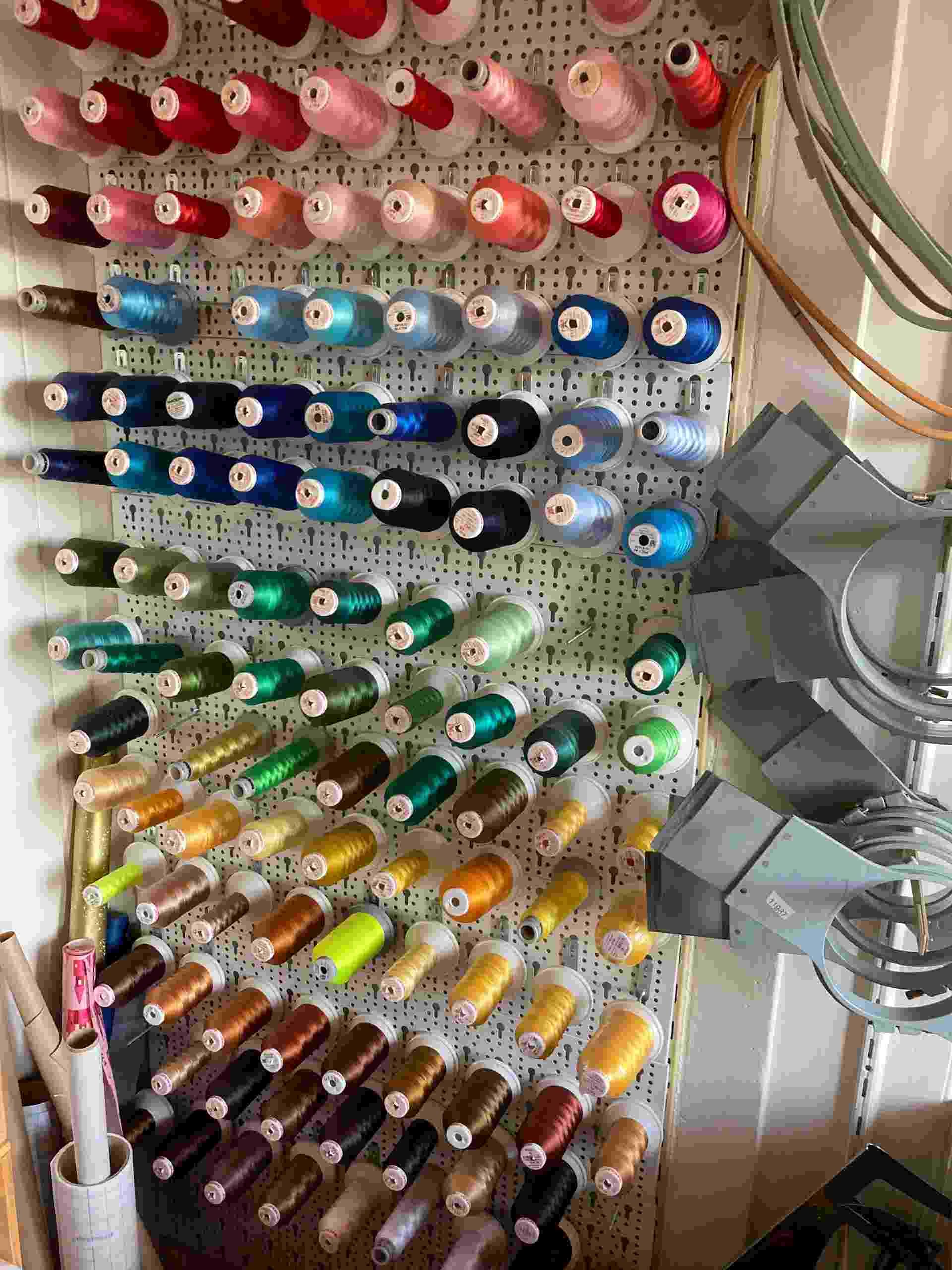 Wanddisplay mit Garnspulen in verschiedenen Farben.